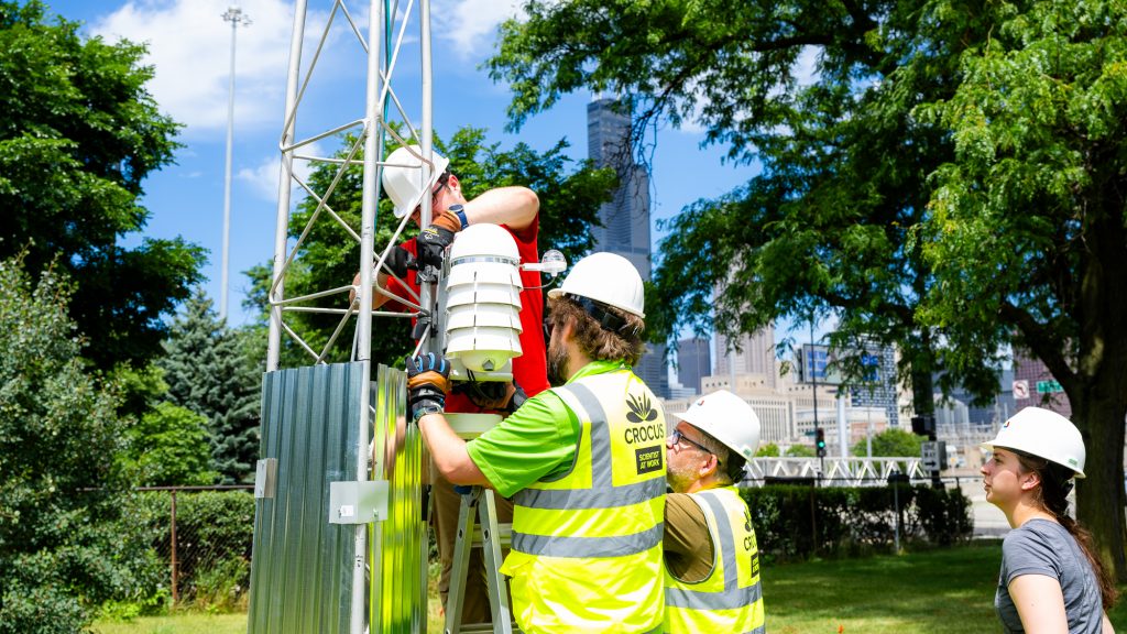 A group of CROCUS team members set-up weather reading instruments in the city of Chicago. The back of their yellow safety vests read 'CROCUS. SCIENCE AT WORK.'